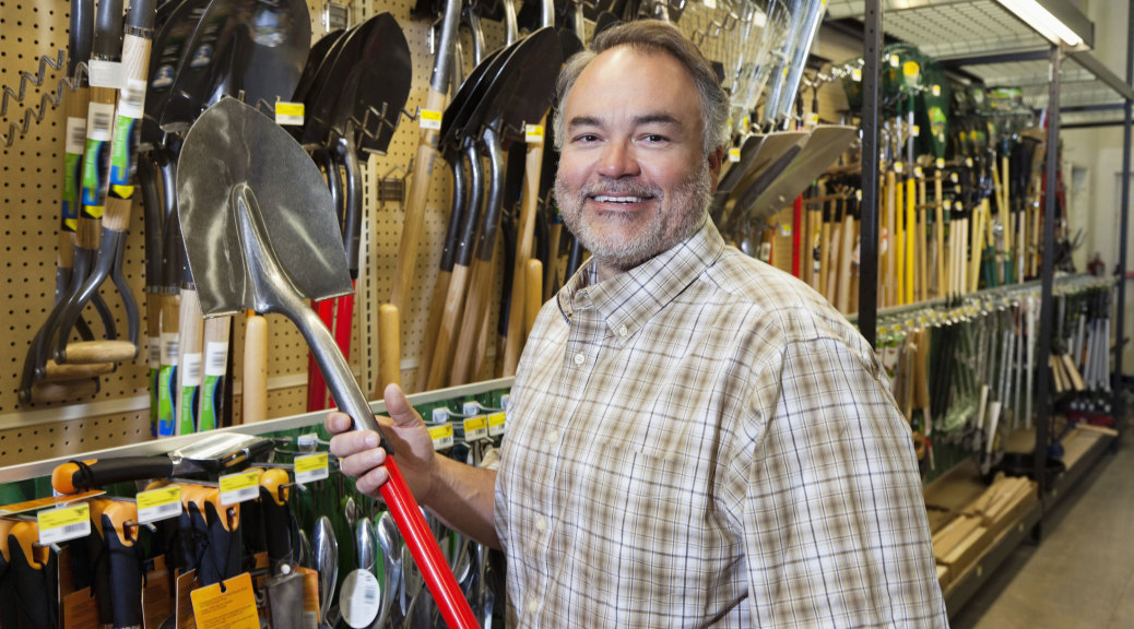 man in a hardware store holding a shovel